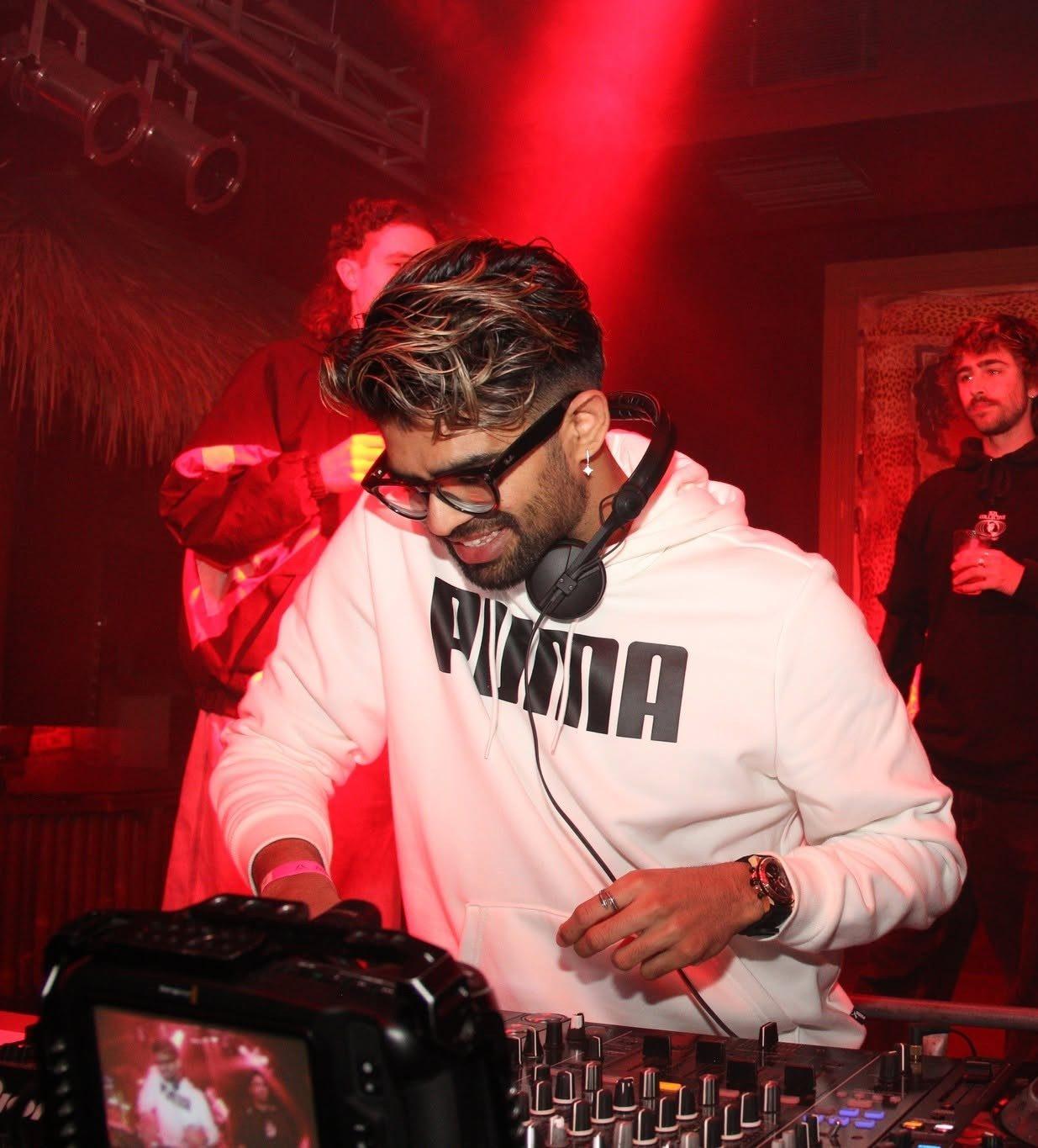 Dr Darp in a white hoodie with headphones on, mixing under red lights