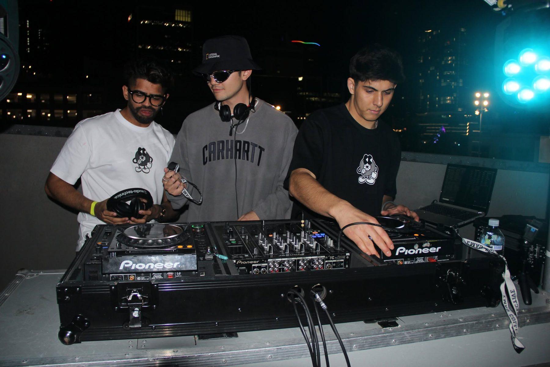 Dr Darp and two other DJs gathered around CDJs on a rooftop at night