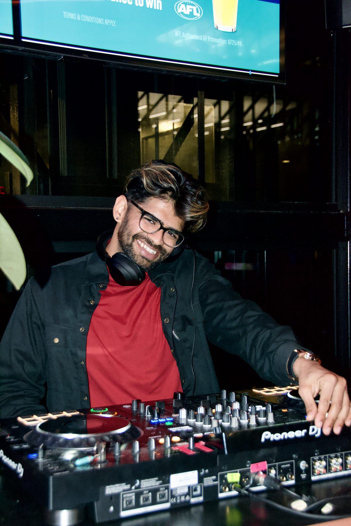 Dr Darp smiling behind the decks in a black jacket